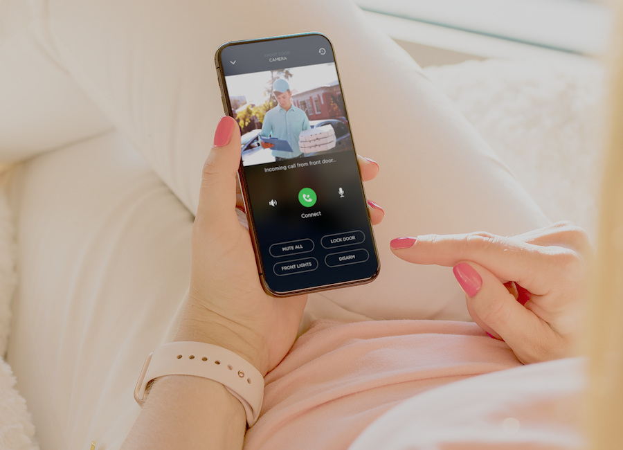 Woman talking to delivery man on her smartphone through doorbell camera.