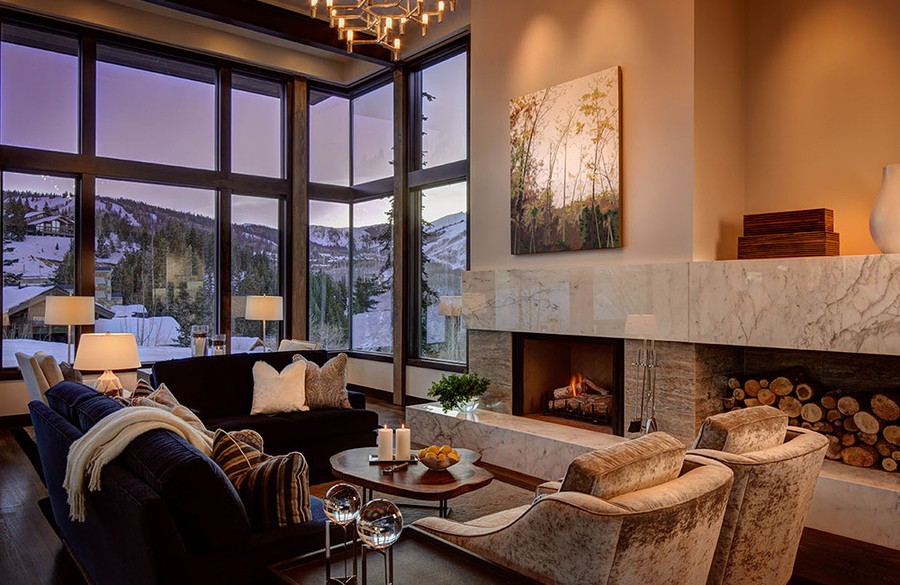 A well-lit living area with a lit fireplace and a few of the snowy mountains.