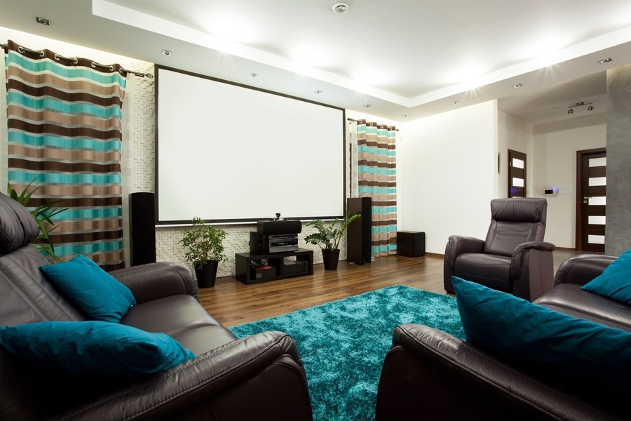 Beautiful in-home theater room with plush gray chairs and teal accents. 