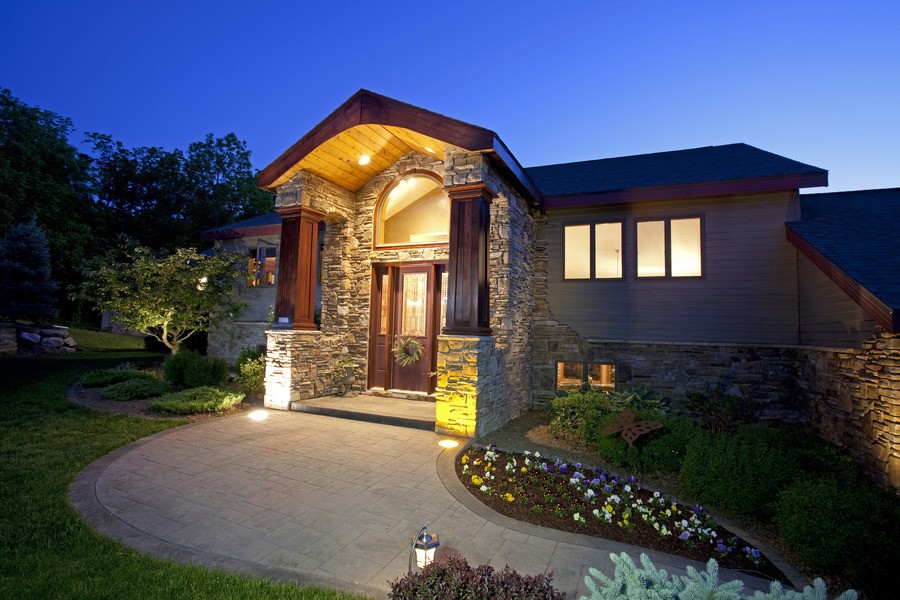 The outside of a beautiful home featuring landscaping and exterior lighting.