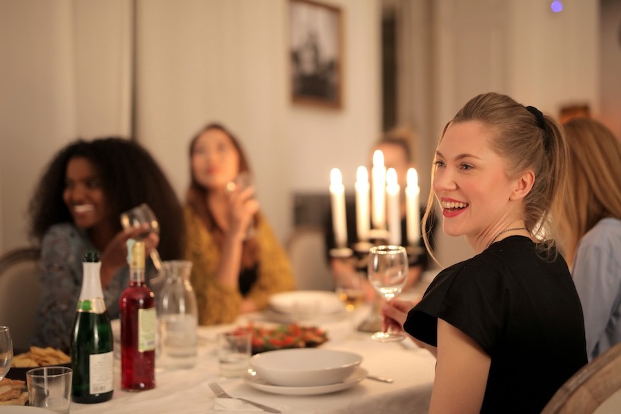 An intimate dinner party with people sitting around a dining table with mood lighting.